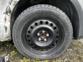 A close-up view of a black steel wheel with circular holes and a mounted tire showcasing the tread pattern and rim details