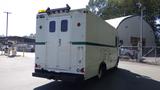 A 2004 Freightliner MT45 delivery truck with a white exterior and green stripe at the rear featuring double doors and roof lights