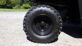 A black tire of a 2016 Polaris Ranger 570 Crew with deep treads mounted on a black wheel