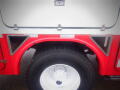 The image shows the rear wheel and fender of a 2012 International 7300 Workstar featuring a large black tire and a red and white fender with reflective accents