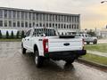 A white 2017 Ford F-350 SD truck with a flatbed and a truck bed rack parked at an angle