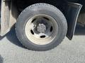 Close-up of a worn tire mounted on a steel wheel of a 2003 Ford F-450 SD showing visible dirt and wear on the tread and rim