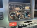 Dashboard controls of a 2013 Isuzu NPR featuring audio system knobs and climate control dials with a digital display showing radio frequency