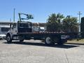 A 2018 International DuraStar flatbed truck with palm trees on the bed parked in a lot
