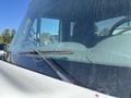 A close-up of a 2007 International 7300 windshield showing a worn wiper blade and a dirty surface with visible dust and grime