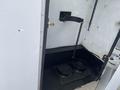 Interior view of a compartment in a 2003 Ford F-450 SD showing a metal hook and chain with a black floor featuring two circular recesses