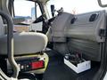 Interior of a 2012 Freightliner M2 112 truck showing the driver's seat dashboard and tools in a box on the floor