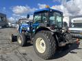 A blue and black 2010 New Holland T4050 tractor featuring large rear tires a front loader attachment and a light on the roof