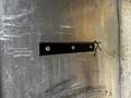 A metal strip with two screws attached to a larger metallic surface, featuring a bent wire loop secured to one end