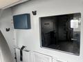 Inside view of a 2016 Chevrolet Express showcasing a clean and functional interior with equipment storage and a window to the driver's area