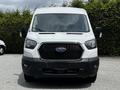 A white 2022 Ford Transit van viewed head-on with a large black grille and distinctive Ford logo in the center