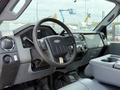 Interior of a 2013 Ford F-550 featuring a steering wheel dashboard controls and center console with storage compartment