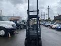 Front view of a 2011 Toyota 028FG15 forklift with raised forks and headlights illuminated