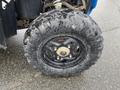 A close-up of a muddy tire from a 2017 Polaris Scrambler showing a rugged tread pattern and a black wheel with visible dirt and wear