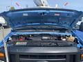 The engine compartment of a blue 2009 Ford Econoline with the hood opened revealing various engine components and fluid reservoirs
