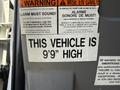 A 2013 Ford Econoline with a sign indicating the vehicle's height is 9 feet
