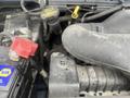 Close-up view of the engine compartment of a 2009 Ford Econoline showing the battery and various engine components with visible wear and dirt accumulation