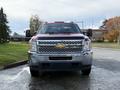 A red 2013 Chevrolet Silverado 3500HD with a chrome grille and a square front design is parked facing the viewer with side mirrors extended