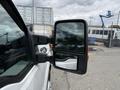 A 2015 Ford F-350 SD side mirror showing an extended view and reflecting surrounding elements