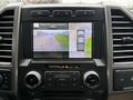 Dashboard display of a 2018 Ford F-150 showing a rearview camera with parking guidelines and a bird's eye view of the truck's surroundings