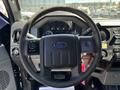 Steering wheel of a 2014 Ford F-250 SD with controls and the Ford logo in the center