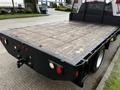 A 2017 Ford F-550 with a flatbed featuring wooden planks and rear lights on both sides