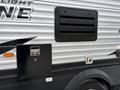 A 2021 Jayco Jay Flight travel trailer featuring a metallic exterior with a black access panel and vent on the side