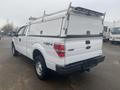 A white 2013 Ford F-150 with a truck cap and 4x4 lettering on the side parked in a lot