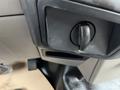 Close-up of the interior control panel of a 2010 Ford F-250 SD featuring a black rotary knob and a small storage compartment below