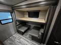 Interior view of a 2021 Grand Design Recreational 311BHS featuring a raised bunk bed area with a wooden surface and two gray upholstered benches on either side