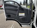 The open door of a 2018 Isuzu NRR showcasing a gray interior panel with a handle and control buttons