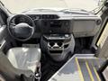 Interior view of a 2010 Ford Econoline showing the dashboard steering wheel and driver's seat with various controls and a cup holder