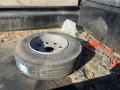 A 2024 Southland 18 Foot Dump Trailer featuring a spare tire with a metal wheel and a chain securing it to the trailer's interior