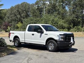 A white 2016 Ford F-150 pickup truck with black accents and chrome wheels parked on a street