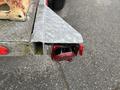 A close-up of the rear light fixture on a 2011 Hightliner Aquacide Hot Water Weed Control Dual Flat Deck Trailer showing a red light and chrome housing