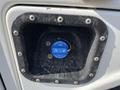 A blue fuel exhaust filler cap located on a 2015 Ford F-450 SD with a black surrounding frame