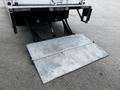 A metallic loading ramp is extended from the back of a 2018 Isuzu NPR truck designed for easy access to the vehicle's cargo area
