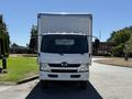 A 2018 Hino 195 truck with a boxy cargo area and prominent front grille parked on a roadway