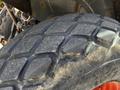 A close-up view of a large tire from a 2011 Kubota M8540D showing a thick tread pattern with visible wear and dirt