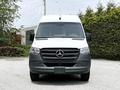A 2023 Mercedes-Benz Sprinter van with a white body and dark gray front bumper featuring the Mercedes logo prominently displayed on the grille
