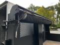 Close-up of a black tarping system with a roller mechanism mounted on a flatbed truck, made for covering loads for transport