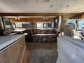 Interior of a 2000 Ford Motorhome featuring a floral-patterned sofa a dining area and a driver's seat with wooden cabinetry and light-colored upholstery
