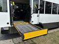 A yellow wheelchair lift extended from the rear of a bus with a 2020 Chevrolet Express design featuring safety handles and a textured surface for stability