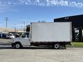 A white 2023 Ford E-450 box truck with a blank side panel and black wheels parked on a concrete surface