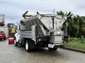A 2013 Ford F-650 equipped with a salt spreader and plow attached to the front in a commercial setting
