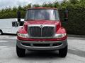 A red 2011 International 4400 truck facing forward with a large grille and side mirrors protruding on either side