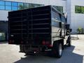 A black 2015 RAM 5500 with a dump bed is parked, showcasing its rear view and distinctive tailgate design