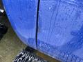A blue 2011 GMC Sierra 3500HD with raindrops on its surface and a visible crack in the paint close to the wheel arch