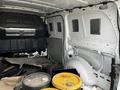 Interior view of a 2018 Mercedes-Benz Metris showing bare metal surfaces and storage space with bins on the floor