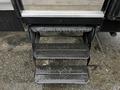 Three metal steps leading up to a travel trailer with a textured surface for traction